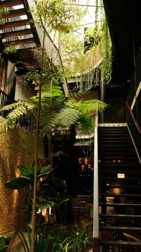 Lush indoor garden with modern stairs and skylight, blending nature with architecture.